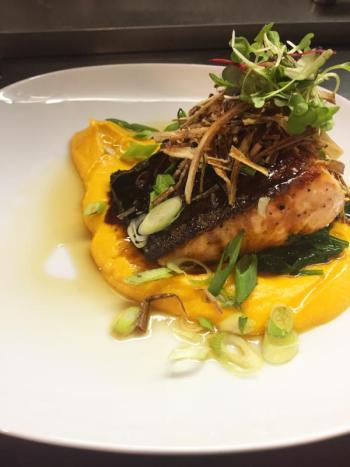 Chef Kelly Farrin’s cast iron roasted skin-on Scottish salmon with sweet potato puree, sauteed spinach, tamari glaze, leek hay strings, fresh scallion and toasted sesame oil, at The Carriage House restaurant in East Boothbay. Courtesy of Kelly Farrin