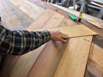 David Nutt applies two layers of red cedar veneer on the already faired hull of Coriolis. SUZI THAYER/Boothbay Register