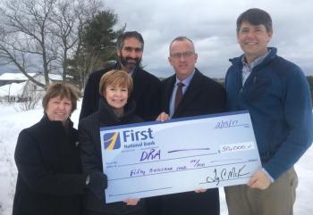 First National Bank presents Damariscotta River Association with a check at DRA Round Top Farm in support of DRA’s capital campaign to enhance education programs, conserve special lands, and protect water quality. Pictured from the left are Emily MacKenzie, DRA leadership gifts chair and former board president; Susan Norton, First National Bank executive vice president and chief administrative officer; Gary Stone, First Advisors vice president and portfolio manager, Tony McKim, First National Bank president and CEO, and Steven Hufnagel, DRA executive director. Courtesy photo