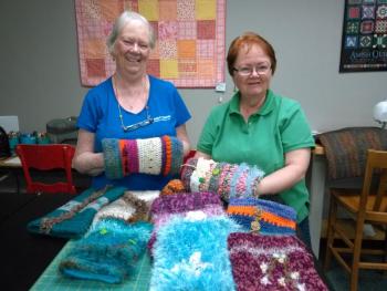 Pat Carmolli, left, of the crochet group and Carol Cragin of the knitting group show twiddle muffs made by fiber artists at the Community Center. The muffs are for dementia patients. JANE CARPENTER/Boothbay Register