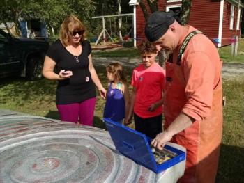 David Sywalski talks to a family about the tools he is using to carving his sculpture. Margaret Hoffman photo Maine Coast Stone Symposium