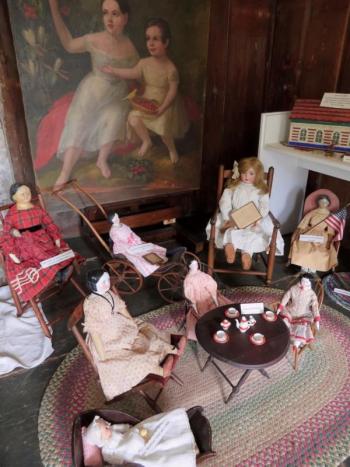 A selection of dolls arranged before a painting of children who lived at the Pownalborough Court House in the mid-1800s were common over the course of nearly 100 years.Courtesy photo