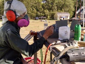 Kamu Nagasawa, visiting from Japan, is working on the smallest sculpture at the Symposium. Margaret Hoffman photo Maine Coast Stone Symposium