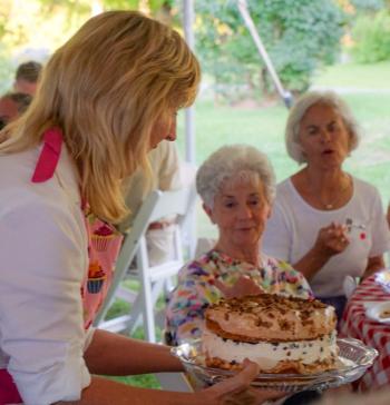 Terri Wells of Wiscasset displays Connie’s Favorite Birthday Cake to guests at Lincoln County Historical Association’s Kermess at Pownalborough Court House. Linda Belmont considers making a bid. Courtesy of Sarah Sutter