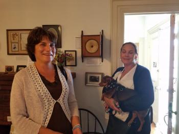 Visitors Linda Thompson, left, and Terri Reynolds (with the dog, Jack), right, on either side of the homemade telephone donated by their maternal grandmother, “Hot Rod Helen.” KATRINA RICKERMANN/Boothbay Register