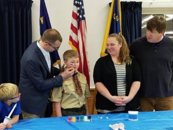 Grahm Cox’s dad Derrick paints a blue, gold and white stripe on his cheek during the boy’s Arrow of Light Ceremony on Feb. 24. Grahm’s mom Lauren is beaming while stepdad David Allen and younger brother Owen (far left) watch with great interest. Courtesy of Robin Ford