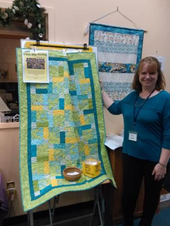 Community Center secretary Jen Field shows the beautiful quilt made by the Center’s “Just Sew” group for a May 15 drawing. JANE CARPENTER/Boothbay Register