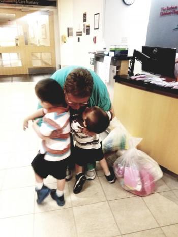 Harjula twins Grant and Luke are greeted by Sue Rainville, one of their original nurses as they deliver knitted caps and blankets from the Community Center to the NICU at the Barbara Bush Children’s Hospital on July 21. Photo courtesy Harley Harjula
