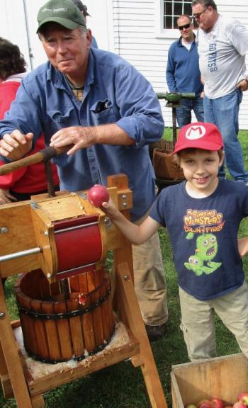 Wiscasset's Ed Kavanagh works the cider press with help from Farmingdale's Josh Grant who was spending the weekend with his grandparents. PHIL DI VECE/Wiscasset Newspaper