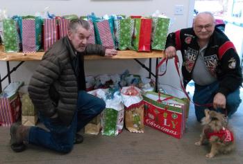 Reid Hodgdon, left, and Daren Graves, assisted by Cinnamon, with gift bags for veterans at the Boothbay Harbor Rotary clubhouse. JANE CARPENTER/Boothbay Register