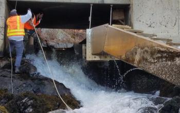 Kipp Farrin, left, and Josh Cook thread the siphon pipe through the dam in the box culvert. Merritt Blakeslee photo