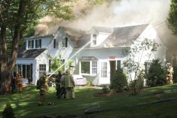 Firefighters work to put out the fire on one side of the Stratton house. STEVE EDWARDS/Boothbay Register