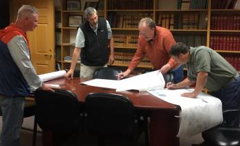 Bill Cloutier of West Newbury, Massachusetts watches as Boothbay Code Enforcement Officer Jason Lorrain, second from left, helps planning board members Bruce Bowler and Rob Ham, right, to sign the mylar plan for registering changes to his Barters Island summer home renovations. BILL PEARSON/Boothbay Register