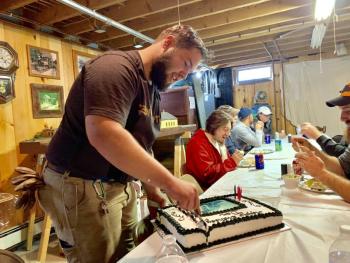 Saturday night at the Percival building named for museum founder Harry Percival, Dan Malkowski cuts his birthday cake to share with the roomful of fellow volunteers who sang him
“Happy Birthday.” SUSAN JOHNS/Wiscasset Newspaper