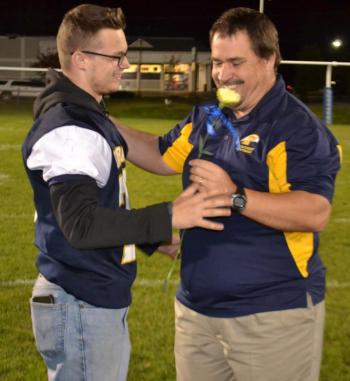 Ben Rumney receives a carnation and congratulations from Coach Ed Crocker during the Oct. 11 Seniors Night celebration. BILL PEARSON/Boothbay Register