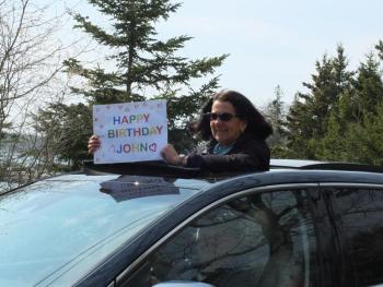 Laura Francis, with Steve Francis driving, shows off a handmade sign for John Druce. BILL PEARSON/Boothbay Register