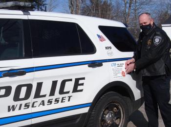 Sgt Hatch of Wiscasset Police Department places a new LTIP decal on his cruiser. Courtesy photo