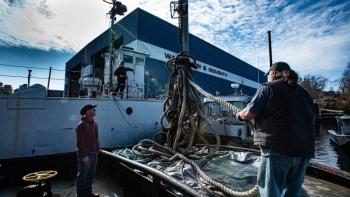 Tugboat crew member Mark Stover brings a tow line onto the tugboat. Jim Fossett photo