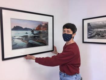 Eva McDermott straightens one of her photographs of Norway, one of 26 in her solo show at Boothbay Region Art Foundation in Boothbay Harbor. LISA KRISTOFF/Boothbay Register