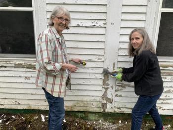 Saturday was too damp to paint, but Rebuilding Together volunteers Judy Adamson, left, and Rosemary Bourette scraped an Ocean Point Road home in preparation for painting later this month. BILL PEARSON/Boothbay Register