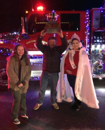 Boothbay Harbor Fire Chief Nick Upham hoists the Dalmation Cup, presented to the department as the winner of the Lighted Fire Truck parade. At his right is judge Suzie Edwards and at his left is judge Kat Pinkham. STEVE EDWARDS/Boothbay Register