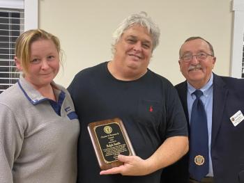 Ralph Smith, center, with wife Elena receives a plaque from Post Commander David Patch. Jim Singer photo