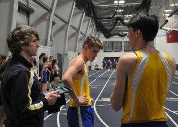 Coach Nick Scott speaks with Fox Elder, center, and Will Perkins at a 2018 meet. File photo