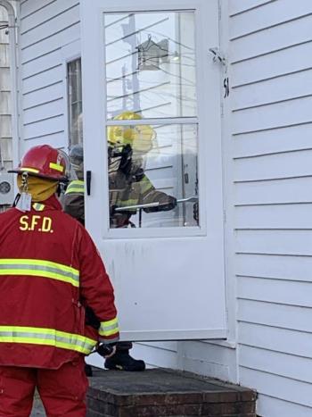 A firefighter uses a tool to enter the locked front door. KEVIN BURNHAM/Boothbay Register