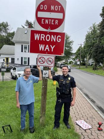 Boothbay Harbor PD Sgt. Jake Powers and Bill Prince of the Rotary Bicycle Program stand next to the new sign on Townsend Avenue at Pear Street alerting bicycle riders not to ride the wrong way. Larry Brown photo