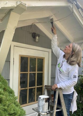 Sally Maroon of Boothbay Harbor paints the entrance of a Wiscasset Road home Sept. 23 during a Rebuilding Together Lincoln County volunteer project in Boothbay. BILL PEARSON/Boothbay Register