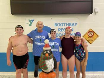 Pictured from left are Byran Hills (12), Officer Larry Brown (70), the Penquin Plunge mascot, Hannah Hills (16), Suzie Edwards (17), and Nathalie Wilson (10) before their annual friendly competitive mini-meet. Courtesy of BRYMCA