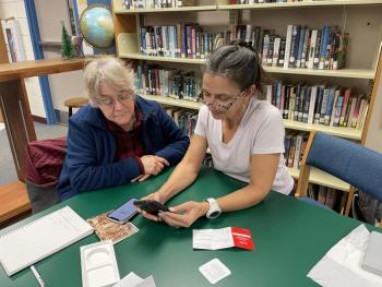 Adult education instructor Ingrid Merrill, right, helps a community member set up a new iPhone. Courtesy of Raye Leonard