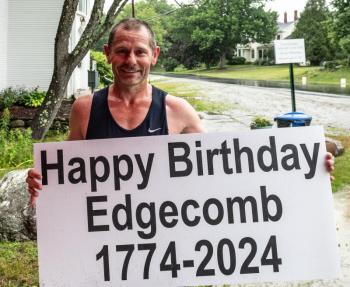 Perry Lebreton holds up a sign wishing the town a happy birthday after winning the 10K leg of the Edgecomb 250th Birthday Road Race on June 22. Lebreton said he has been running since 1988 and estimates that he’s logged half a million miles in his lifetime. Bisi Cameron Yee photo
