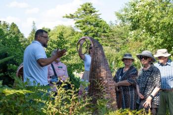 Attendees look at the Shane Perley-Dutcher, Eci-Mahsosiyil/Fiddleheads sculptures (2024). Courtesy of Coastal Maine Botanical Gardens