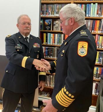 Brigadier General Paul Smith presents Gerry Gamage with a special coin in recognition of his hanging all 150 veterans banners this year. BILL PEARSON/Boothbay Register coin