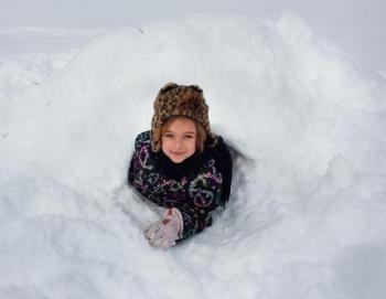 A Coastal Rivers camper shows off her quinzee, a type of snow shelter. Courtesy of Coastal Rivers