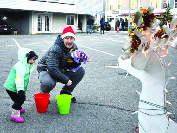 Reese Washburn, 3, tosses a ring to a reindeer with her father, David. FRITZ FREUDENBERGER/Boothbay Register