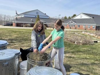 Sixth grade helpers Briar, daughter of Arianna and Brice Johnson, and Lilianna, daughter of Trista and Brian Cassidy, sprinkle hay between layers of compost in one of eight 31-gallon bins, donated by Ames True Value of Wiscasset and an EES teacher.  Students are residents of Alna and Edgecomb. Courtesy photo