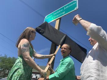 From left, Heather Jones and State Sen. Rachel Talbot Ross unveil one of the new signs naming the Main Street, Wiscasset railroad crossing James Weldon Johnson Crossing, as Terry Heller holds a phone on which Johnson’s great niece Melanie Edwards and Tony Hill, past lawmaker in Johnson’s native Florida, attend via Zoom June 26. Johnson, the poet-civil rights advocate who wrote the words to “Lift Every Voice and Sing,” died in a car-train crash at the crossing in 1938. SUSAN JOHNS/Wiscasset Newspaper 