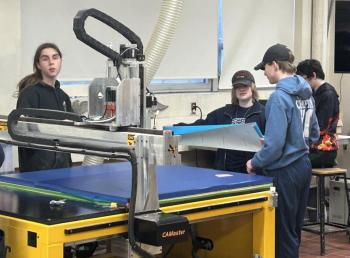 Preston Giles, Abby Orchard, and Nathan Perceival prepare materials by the CNC router while Brandon Seigers loads the file on the computer. Courtesy of Chris Liberti.