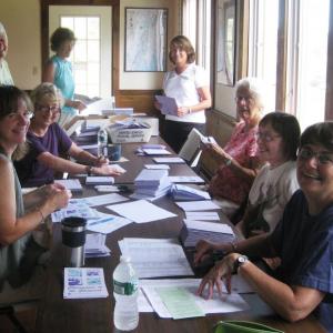 Sheepscot Valley Conservation Association staff and volunteers Kristin Pennock, Ann Springhorn, Honor Sage, Suki Flanagan, Carole Dunbar, Nancy Hartley, Callie Wronker and Beth Quivey prepare invitations to the Champagne on the Sheepscot fundraiser.