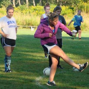 Soccer coach Kate Hossler demonstrates a strong and proper kick to the 17-member Lady Seahawks team at a recent practice. Below, Anna Baumm (left) and Brenna Alley vie for the ball during a scrimmage at the August 30 team practice. LISA KRISTOFF/Boothbay Register Soccer coach Kate Hossler demonstrates a strong and proper kick to the 17-member Lady Seahawks team at a recent practice.