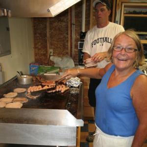 Lisa McSwain cooks the hamburgers and hot dogs while fellow Boosters Club member Andrew Morley brings more burgers to the grill during the August 31 home football game. KEVIN BURNHAM/Boothbay Register Lisa McSwain cooks the hamburgers and hot dogs while fellow Boosters Club member Andrew Morley brings more burgers to the grill during the August 31 home football game. KEVIN BURNHAM/Boothbay Register
