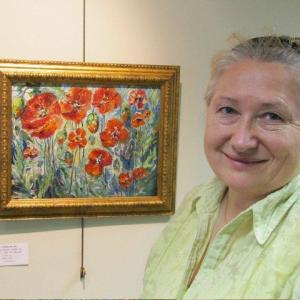 Svetlana Beattie shown with one of her paintings at the FIRST Bank in Boothbay Harbor. 