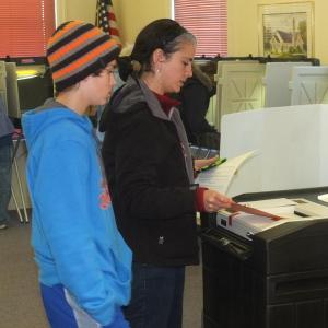 Sarah Goodroe inserts the ballot into the machine as her son Eli watches at the Boothbay Town Office, November 6. 