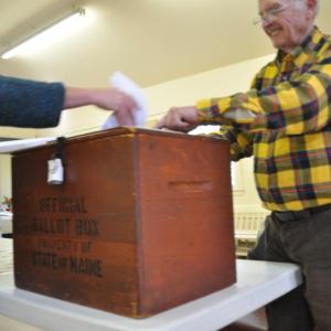 Donna Climo, left, puts ballots in the ballot box as Ronald Orchard, right, watches on Tuesday in Southport. BEN BULKELEY/Boothbay Register