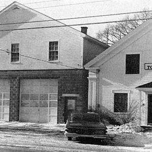 This Boothbay Center shot, from the 1961-1962 Boothbay town report, shows the new cement block garage with town office upstairs, as well as the 1848 town hall. George McEvoy preserved the town hall from being demolished, moving it to the Railway Village in 1990 where it was put in good repair. After the garage/office stood empty and unsold for some time, McEvoy also bought and repaired it, greatly improving its looks.