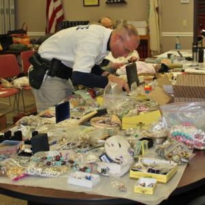 Officer Mercier searches through some of the goods recovered from the Fuller residence at Boothbay Harbor Town Office March 28. Police have thousands of items to sort through and compare to individual itemized lists from area burglaries. SUE MELLO/Boothbay Register
