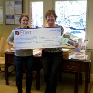 Abby Plummer, aka “Farm Abby” of the Morris Farm, left, accepts a check from Monique McRae, Wiscasset Branch Manager of The First for the Wiscasset Primary School’s garden project at the Morris Farm. Courtesy of The First