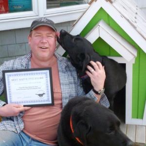 Owner Don Kingsbury holds Two Salty Dog’s award, as Max the lab decides this “photo opportunity” would be better served as a puppy-kiss opportunity. Coal the lab relaxes in front.  KATRINA CLARK/Boothbay Register